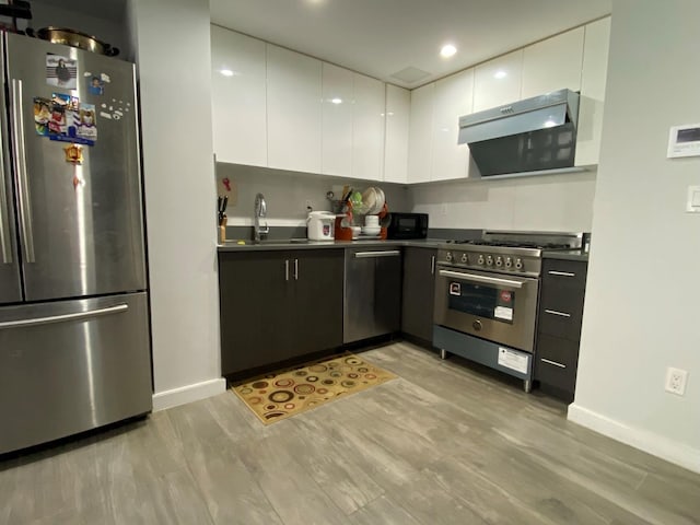 158-15 Union Tpke Unit 2D, Fresh Meadows, NY 11366 - kitchen with stainless steel appliances, under cabinet range hood, dark countertops, light wood-style floors, and recessed lighting