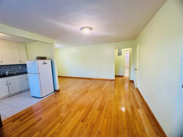 196-58 69th Ave Unit 1, Fresh Meadows, NY 11365 - kitchen with freestanding refrigerator, white cabinetry, light wood-style floors, and backsplash