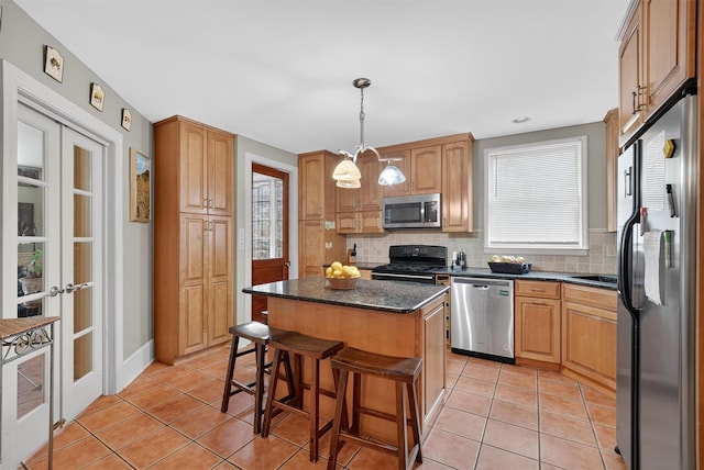 13 Garfield Pl, Poughkeepsie, NY 12601 - kitchen featuring appliances with stainless steel finishes, tasteful backsplash, a center island, light tile patterned floors, and a breakfast bar area