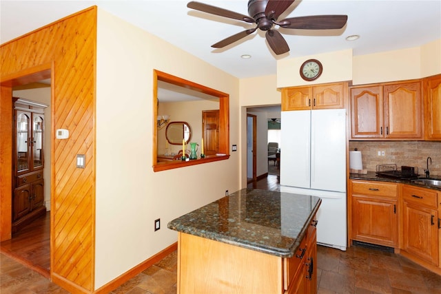 66 Parma Rd, Island Park, NY 11558 - kitchen with freestanding refrigerator, tasteful backsplash, dark stone countertops, a ceiling fan, and a center island
