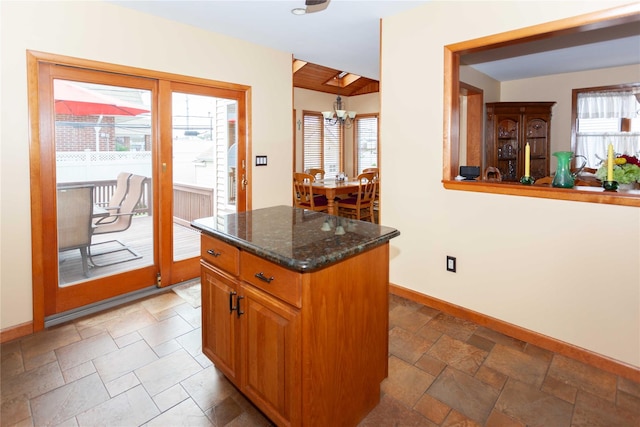 66 Parma Rd, Island Park, NY 11558 - kitchen with healthy amount of natural light, stone tile floors, a chandelier, and dark stone counters