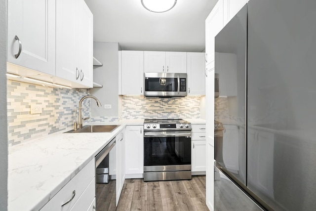 55 Mckinley Ave Unit D3-14, White Plains, NY 10606 - kitchen with stainless steel appliances, light wood-type flooring, white cabinetry, decorative backsplash, and light stone countertops