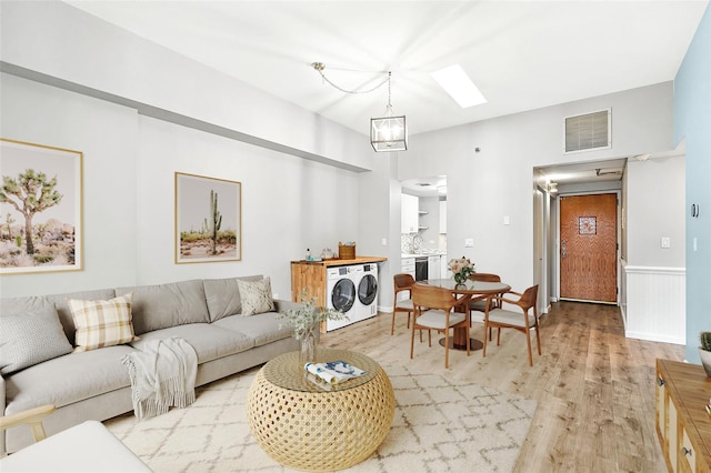 55 Mckinley Ave Unit D3-14, White Plains, NY 10606 - living room featuring washing machine and dryer, light wood-style floors, a skylight, and a chandelier