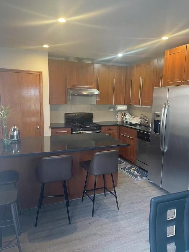 173-02 Effington Ave, Flushing, NY 11358 - kitchen with appliances with stainless steel finishes, a kitchen breakfast bar, light wood-type flooring, under cabinet range hood, and recessed lighting