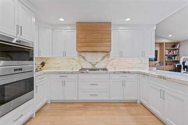 63 Sutton Pl, Manhasset, NY 11030 - kitchen with wall chimney exhaust hood, stainless steel appliances, white cabinetry, decorative backsplash, and recessed lighting