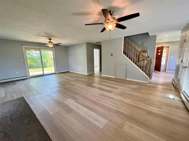 23 Chase Ln, Levittown, NY 11756 - unfurnished living room with a ceiling fan, stairs, light wood finished floors, and a baseboard heating unit