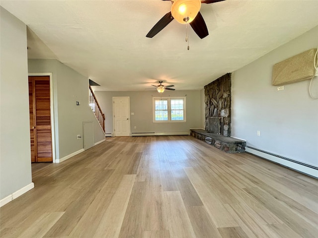 23 Chase Ln, Levittown, NY 11756 - unfurnished living room with a ceiling fan, stairway, light wood-style floors, a stone fireplace, and a baseboard heating unit