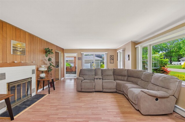 16 Colonial Dr, East Patchogue, NY 11772 - living area with a baseboard heating unit, light wood-style flooring, wood walls, and a fireplace with flush hearth