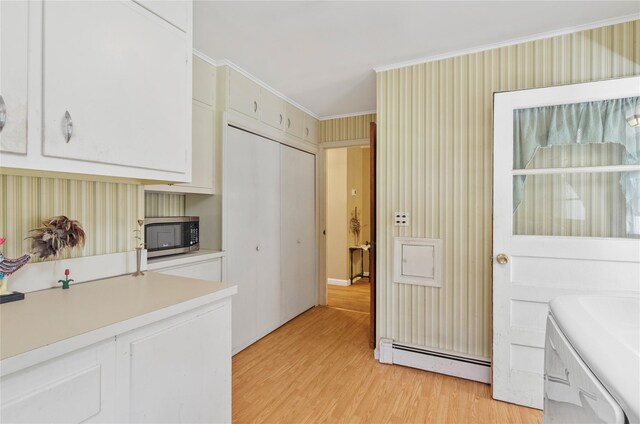 16 Colonial Dr, East Patchogue, NY 11772 - kitchen with a baseboard radiator, stainless steel microwave, light wood-style floors, light countertops, and white cabinetry