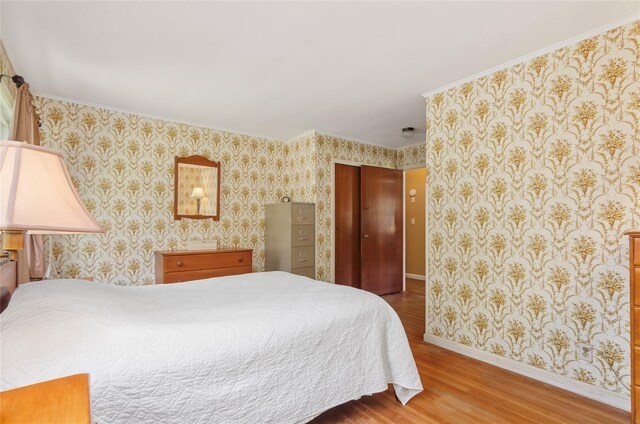 16 Colonial Dr, East Patchogue, NY 11772 - bedroom featuring wood finished floors, wallpapered walls, a closet, and crown molding