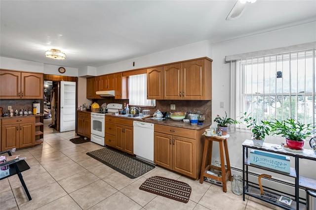 1541 Herzel Blvd, West Babylon, NY 11704 - kitchen featuring white appliances, under cabinet range hood, tasteful backsplash, brown cabinetry, and light tile patterned flooring