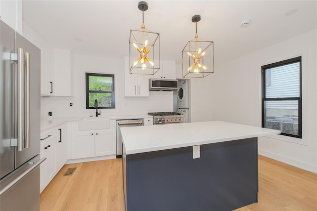 231 Macdougal St, Brooklyn, NY 11233 - kitchen featuring appliances with stainless steel finishes, estacked washer and dryer, light wood-style flooring, and a chandelier