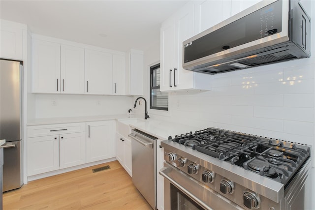 231 Macdougal St, Brooklyn, NY 11233 - kitchen featuring appliances with stainless steel finishes, decorative backsplash, white cabinets, and light wood-type flooring