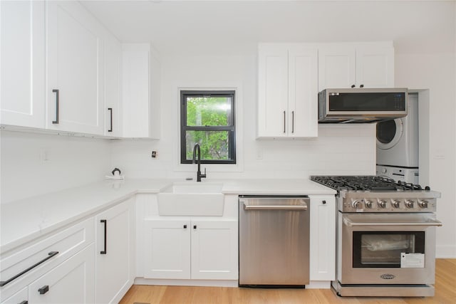 231 Macdougal St, Brooklyn, NY 11233 - kitchen with stainless steel appliances, stacked washer and clothes dryer, decorative backsplash, and white cabinetry