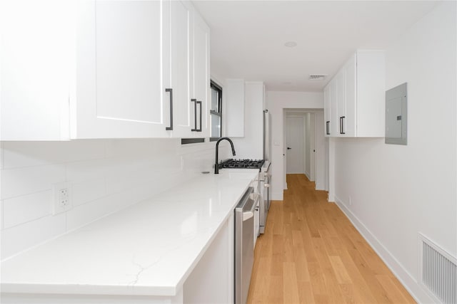 231 Macdougal St, Brooklyn, NY 11233 - kitchen featuring electric panel, white cabinetry, light wood-type flooring, light stone counters, and stainless steel appliances