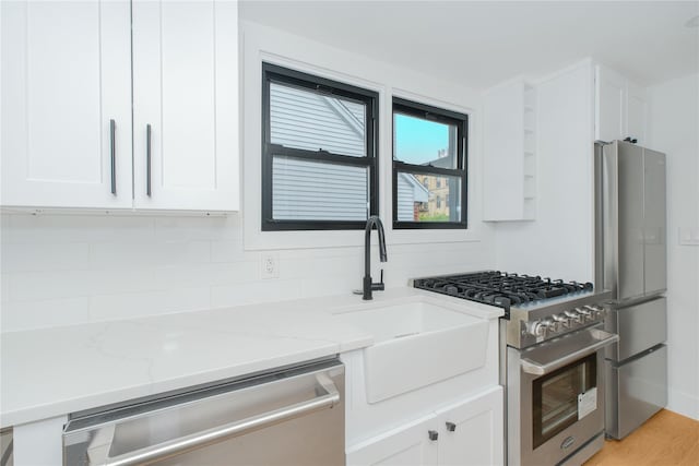 231 Macdougal St, Brooklyn, NY 11233 - kitchen featuring stainless steel appliances, white cabinetry, light stone countertops, tasteful backsplash, and light wood-style flooring
