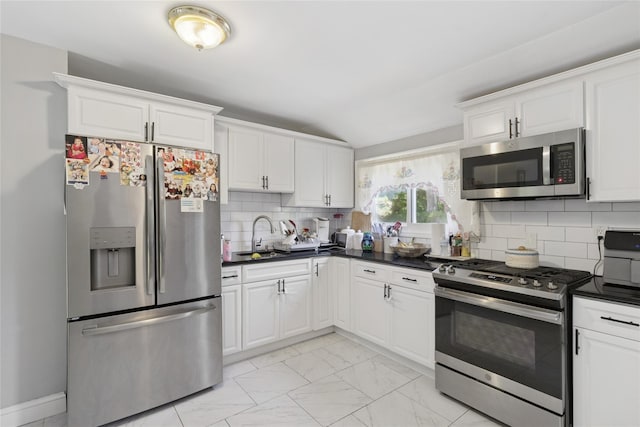 2 Prospect St, Central Islip, NY 11722 - kitchen featuring appliances with stainless steel finishes, dark countertops, light marble finish flooring, backsplash, and white cabinetry