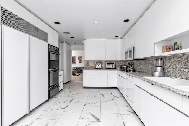 895 Cherry Ln, North Woodmere, NY 11581 - kitchen with paneled refrigerator, white cabinetry, light marble finish floors, stainless steel microwave, and backsplash
