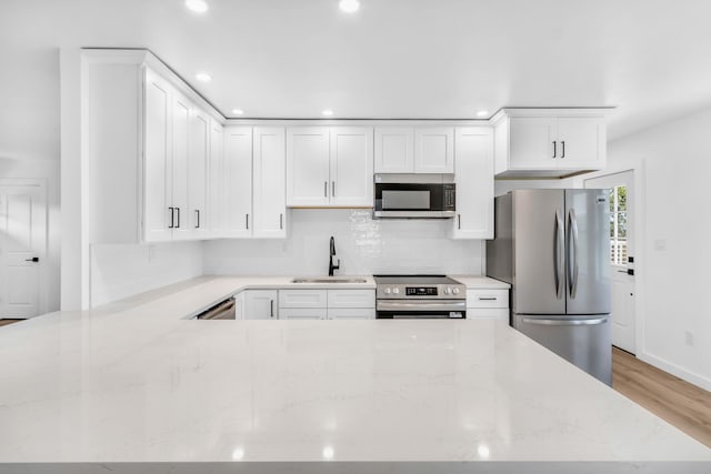 50 Appletree Dr, Saugerties, NY 12477 - kitchen with stainless steel appliances, white cabinetry, light wood-style floors, a peninsula, and light stone counters