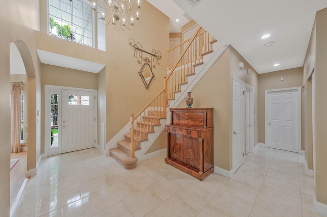 28 Hamlet Dr, Commack, NY 11725 - entryway with stairway, arched walkways, a chandelier, tile patterned flooring, and a towering ceiling