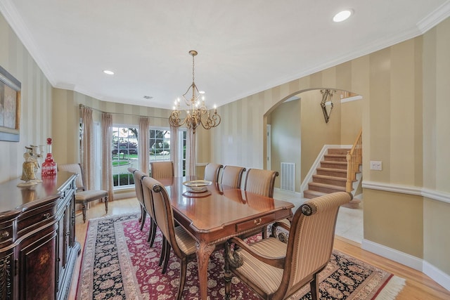 28 Hamlet Dr, Commack, NY 11725 - dining space with arched walkways, ornamental molding, a chandelier, stairs, and light wood finished floors