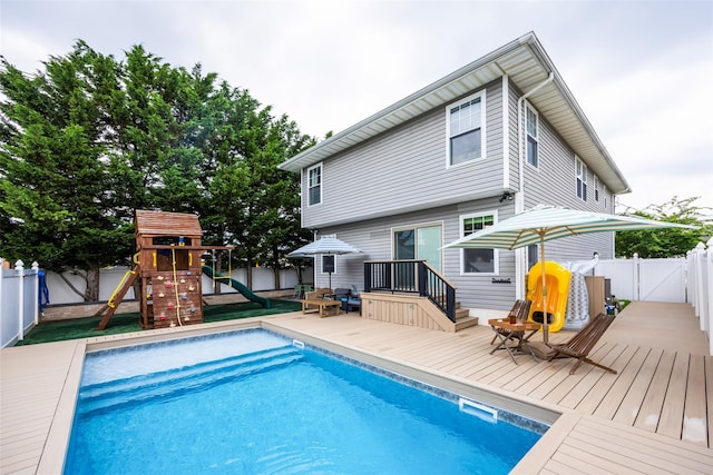 1200 Roger Rd, North Bellmore, NY 11710 - view of swimming pool with a wooden deck, a fenced backyard, a playground, and a gate
