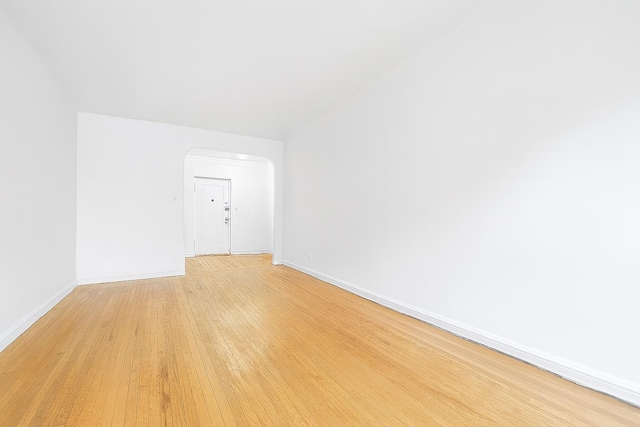 63109 Saunders St Unit 3A, Rego Park, NY 11374 - spare room with light wood finished floors and arched walkways