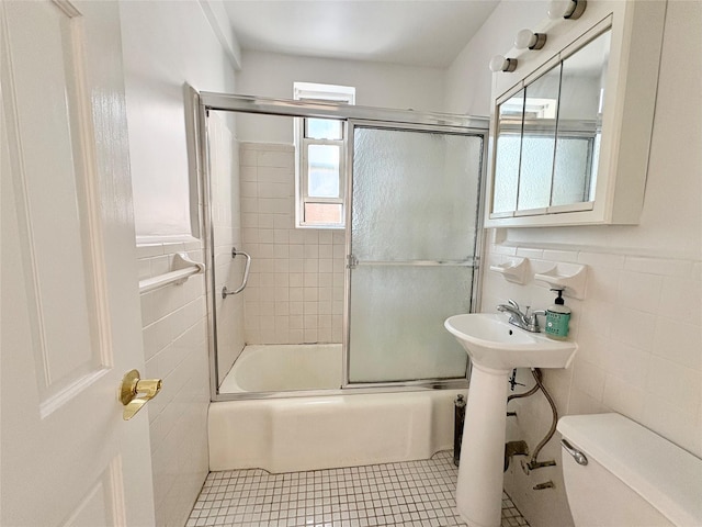 63-61 Yellowstone Blvd Unit 3E, Forest Hills, NY 11375 - bathroom featuring tile walls, bath / shower combo with glass door, tile patterned floors, and a wainscoted wall