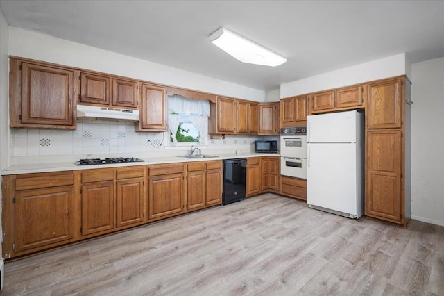 32 Brady Ave, New Rochelle, NY 10805 - kitchen with black appliances, under cabinet range hood, brown cabinets, and light countertops