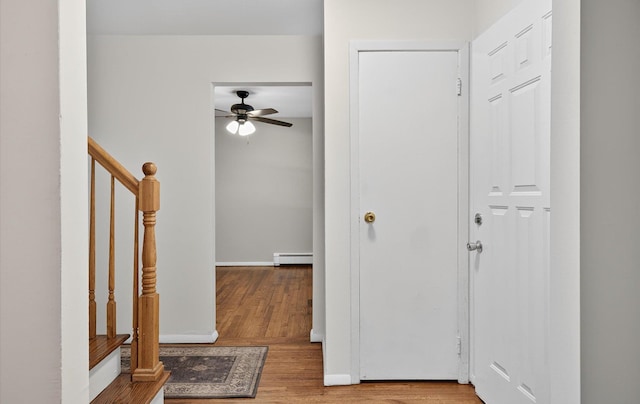 1152 N Country Rd, Stony Brook, NY 11790 - entrance foyer featuring a baseboard heating unit, a ceiling fan, wood finished floors, and stairs