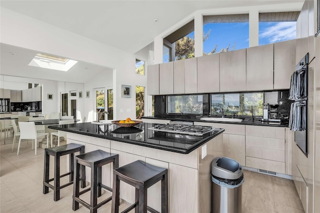 146 Ocean Walk, Fire Island Pines, NY 11782 - kitchen featuring a skylight, a breakfast bar, a center island, stainless steel gas cooktop, and high vaulted ceiling