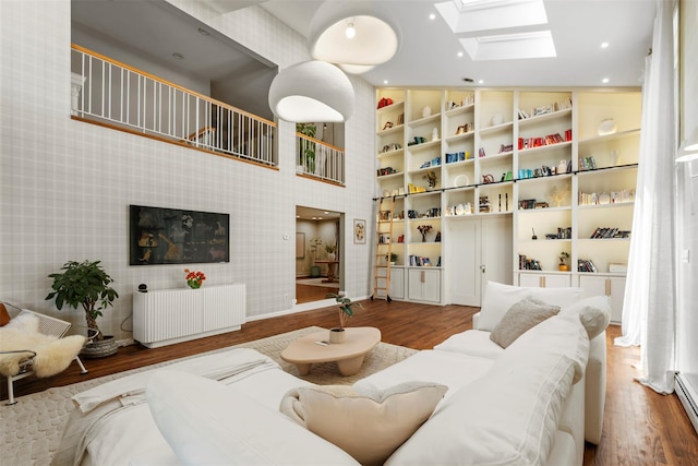 10 Spectrum Dr, Chester, NY 10918 - living room featuring radiator heating unit, a skylight, wood finished floors, built in shelves, and a baseboard radiator