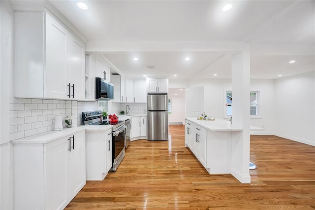 17 Pinetree Dr, Shirley, NY 11967 - kitchen with appliances with stainless steel finishes, light countertops, light wood-type flooring, backsplash, and white cabinetry
