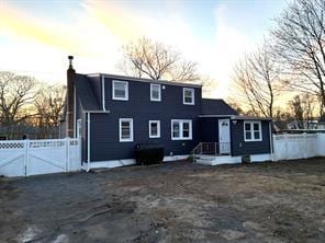 17 Pinetree Dr, Shirley, NY 11967 - back of house at dusk with a chimney and a gate