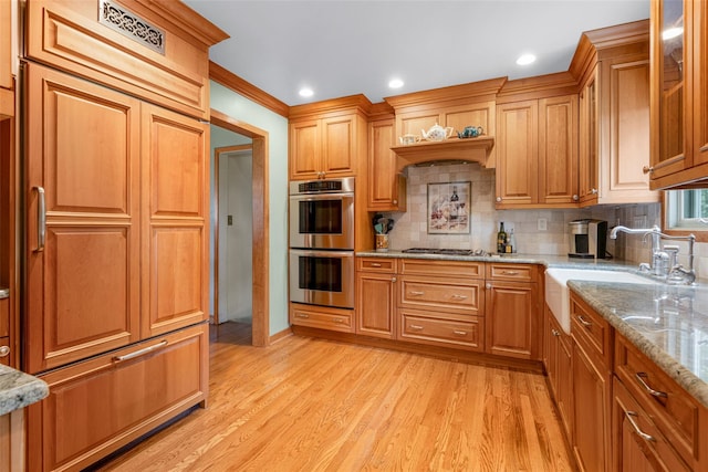 918 Sylvan Ln, Mamaroneck, NY 10543 - kitchen with stainless steel double oven, light stone counters, backsplash, light wood-style flooring, and recessed lighting