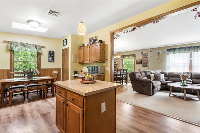 61 Travis Blvd, Catskill, NY 12414 - kitchen with a wainscoted wall, light countertops, light wood-style floors, brown cabinetry, and decorative light fixtures