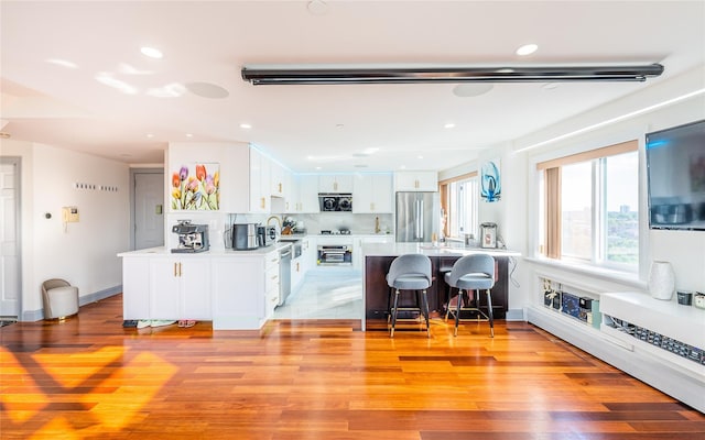 4318 Main St Unit 12A, Flushing, NY 11355 - kitchen with appliances with stainless steel finishes, a kitchen bar, white cabinets, light countertops, and a peninsula
