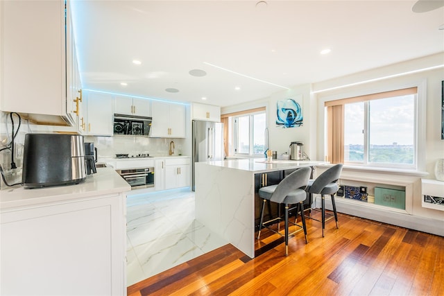 4318 Main St Unit 12A, Flushing, NY 11355 - kitchen with stainless steel appliances, plenty of natural light, a kitchen breakfast bar, white cabinetry, and recessed lighting