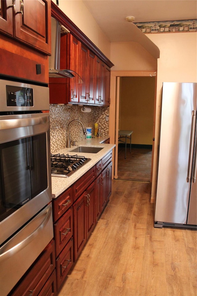30-12 84th St, East Elmhurst, NY 11370 - kitchen featuring stainless steel appliances, a warming drawer, tasteful backsplash, light wood-type flooring, and wall chimney range hood