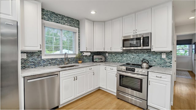 3 Yale, Hampton Bays, NY 11946 - kitchen featuring appliances with stainless steel finishes, light wood finished floors, decorative backsplash, white cabinetry, and recessed lighting