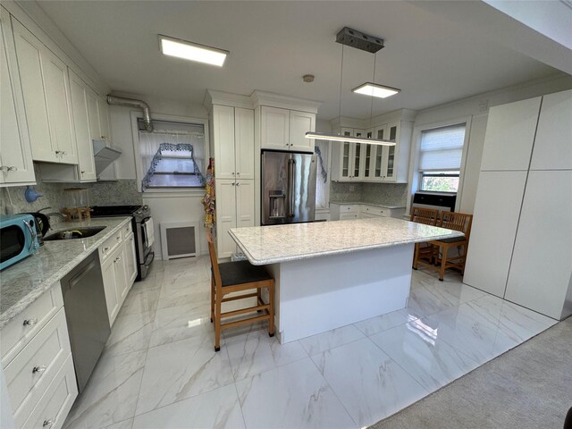 6360 102nd St Unit B19, Rego Park, NY 11374 - kitchen featuring stainless steel appliances, light marble finish flooring, a kitchen island, decorative backsplash, and glass insert cabinets