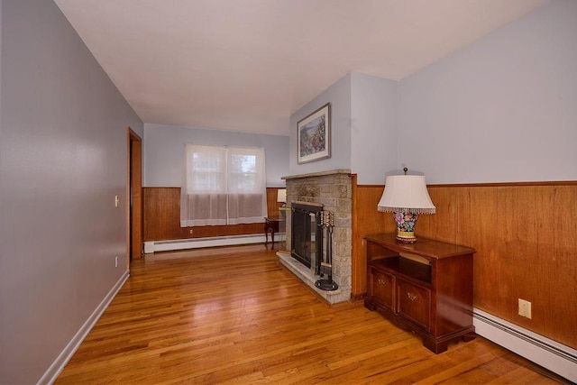 152 Bart Dr, Poughkeepsie, NY 12603 - living area with a baseboard heating unit, a wainscoted wall, a fireplace, and light wood finished floors