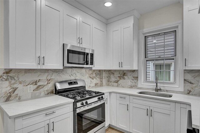 58-60 78th Ave, Glendale, NY 11385 - kitchen featuring appliances with stainless steel finishes, tasteful backsplash, white cabinets, and light stone countertops