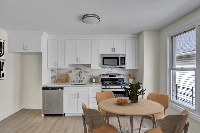 58-60 78th Ave, Glendale, NY 11385 - kitchen featuring appliances with stainless steel finishes, tasteful backsplash, light wood-style floors, white cabinetry, and light countertops