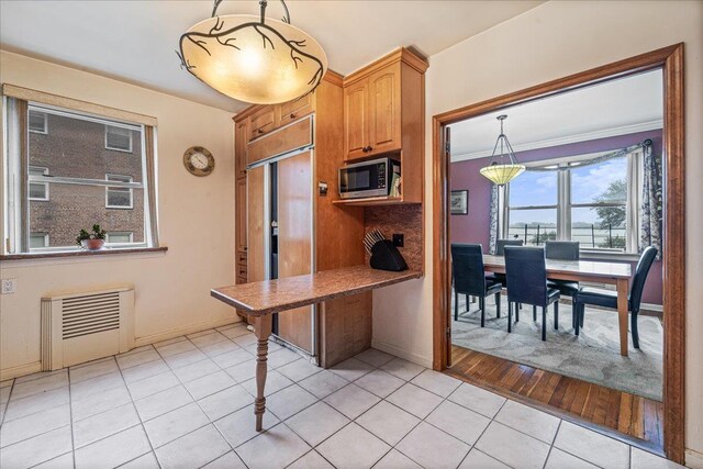 162-41 Powells Cove Blvd Unit 4D, Beechhurst, NY 11357 - kitchen with stainless steel microwave, paneled built in refrigerator, light tile patterned floors, hanging light fixtures, and ornamental molding