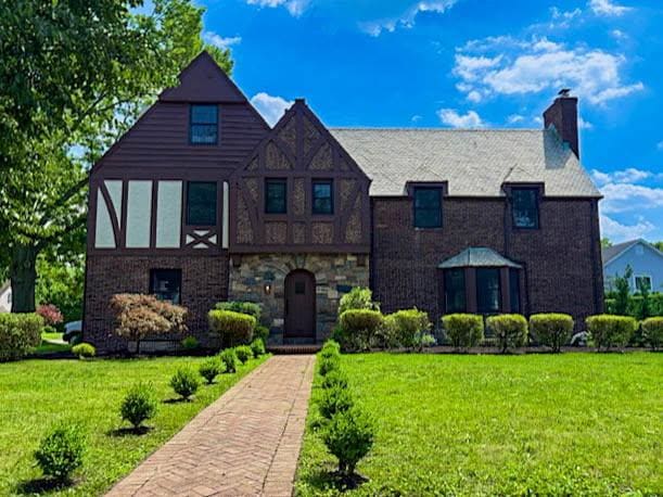 236 Stewart Ave, Garden City, NY 11530 - tudor home featuring a front yard, a chimney, and brick siding