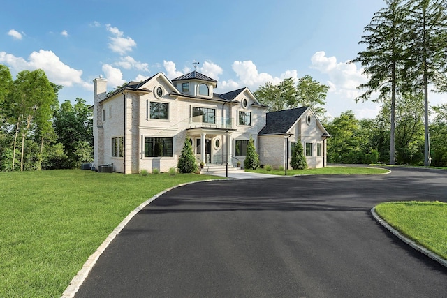 26 Saint Andrews Ct, Old Westbury, NY 11568 - view of front of home featuring a chimney, driveway, a front lawn, and a balcony