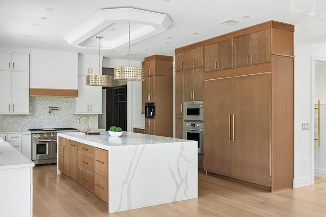 26 Saint Andrews Ct, Old Westbury, NY 11568 - kitchen featuring range with two ovens, light wood finished floors, decorative backsplash, an island with sink, and light stone counters