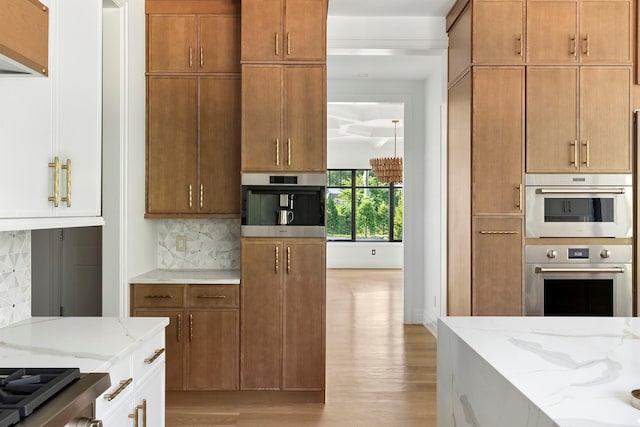 26 Saint Andrews Ct, Old Westbury, NY 11568 - kitchen featuring light wood finished floors, light stone counters, decorative backsplash, and stainless steel double oven