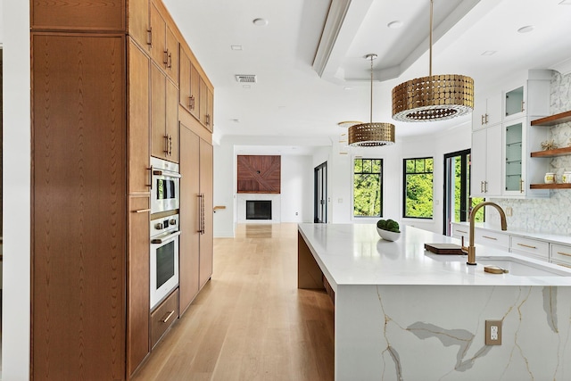 26 Saint Andrews Ct, Old Westbury, NY 11568 - kitchen with open shelves, oven, decorative backsplash, a fireplace, and light wood-style flooring
